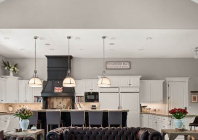 Modern luxury kitchen in new construction home with a vaulted ceiling, custom white cabinetry, and stylish hanging light fixtures.