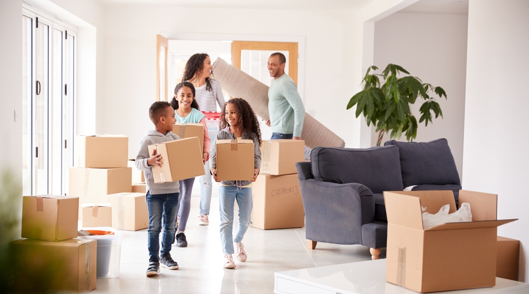 Joyful family moving into their new home carrying boxes in a bright, spacious living room, signaling a fresh start