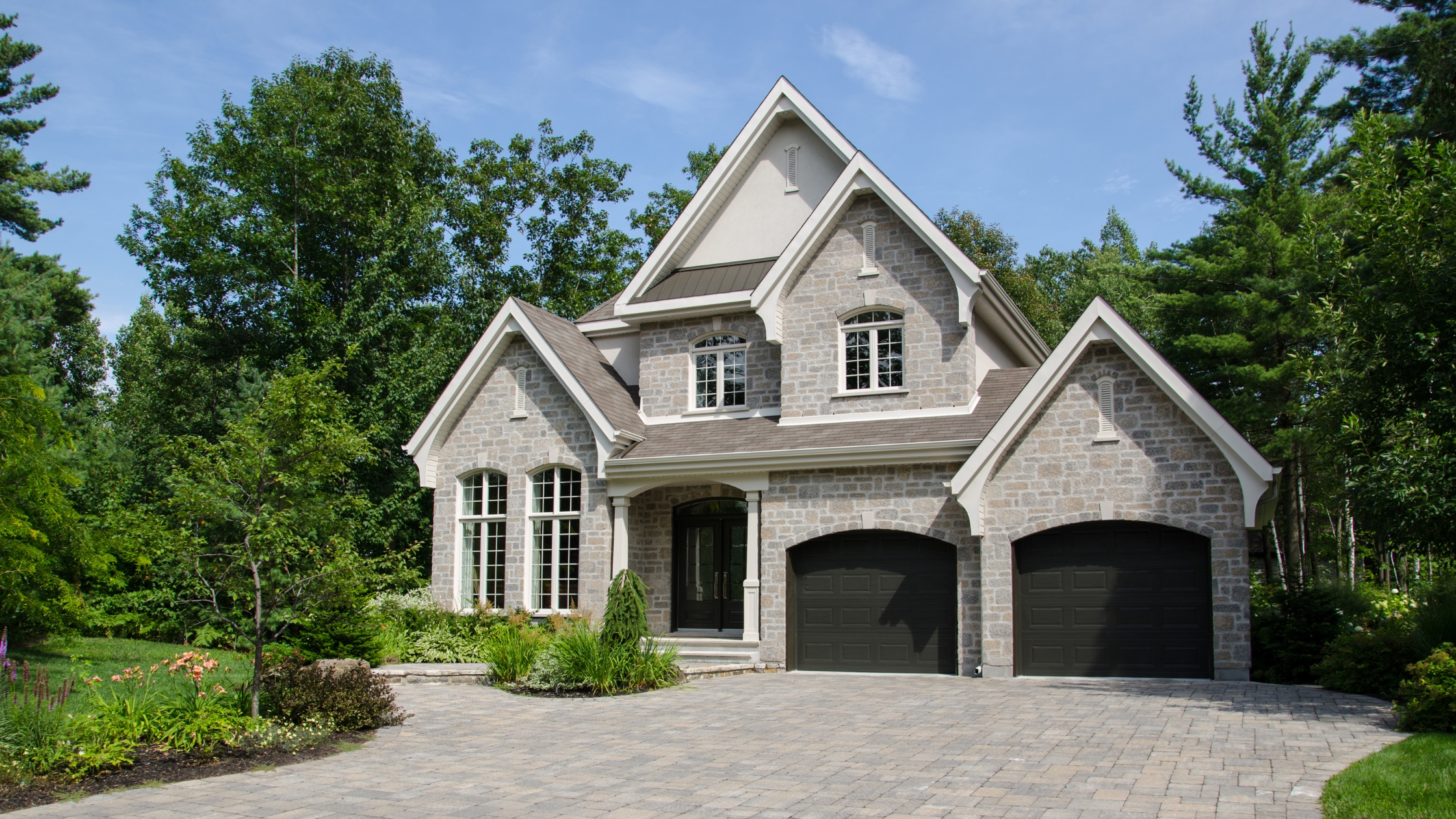 Newly constructed luxury custom home with stone facade and lush landscaping in Utah's serene residential area